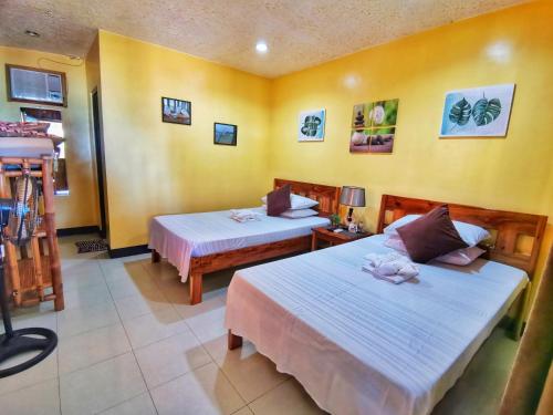 two beds in a room with yellow walls at Besaga Beachfront B&B - Port Barton in San Vicente