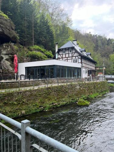 un edificio en una colina junto a un río en Pension Soutěsky, en Hřensko