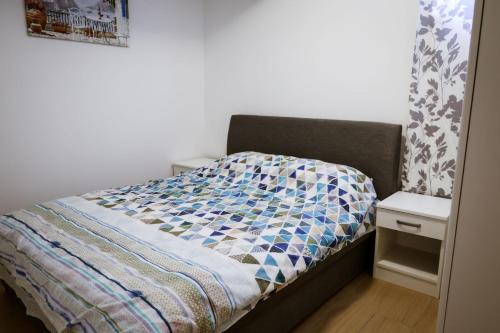 a bed with a quilt on it in a bedroom at Apartment Neiv in Tivat