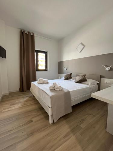 Schlafzimmer mit einem großen weißen Bett und Holzböden in der Unterkunft MoMa B&B in Corigliano Calabro