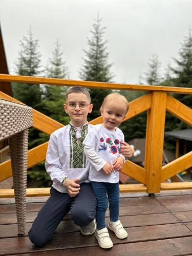 two young boys are sitting on a deck at Karpaty Migovo in Migovo