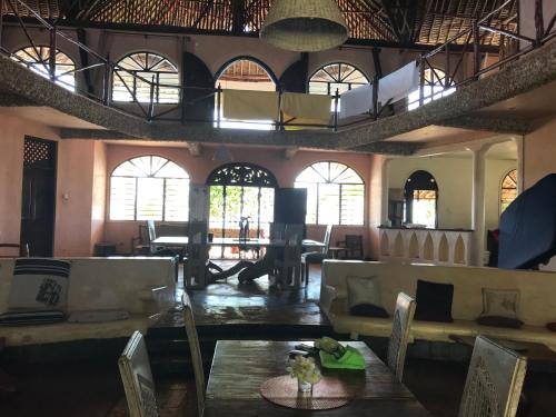 a living room with tables and chairs and windows at Room in Villa - A 37m2 suite in a 560 m2 Villa, Indian Ocean View in Shimoni