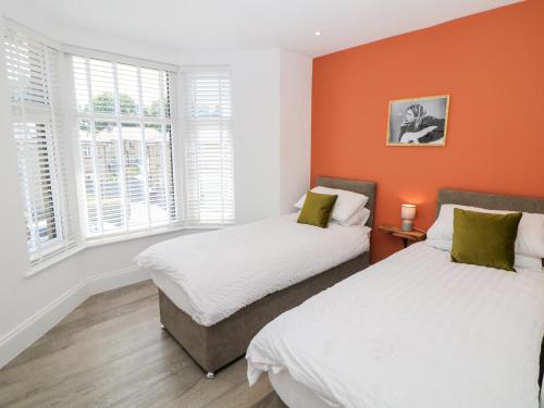 two beds in a room with orange walls and windows at By the Tracks in Buxton