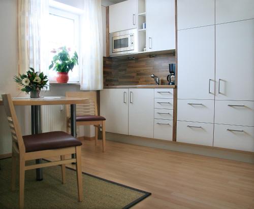a kitchen with white cabinets and a table and chairs at Hotel Linner in Erding
