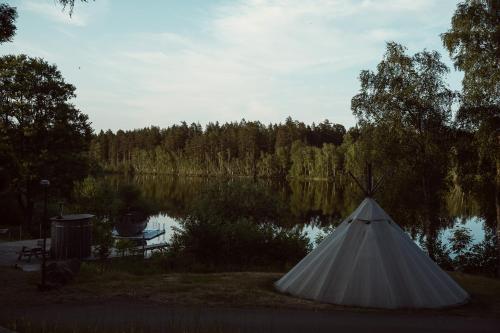a white teepee in front of a lake at Ödevata Gårdshotell in Emmaboda