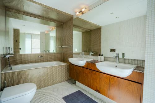 a bathroom with two sinks and a tub and a toilet at Nasma Luxury Stays - Limestone House in Dubai