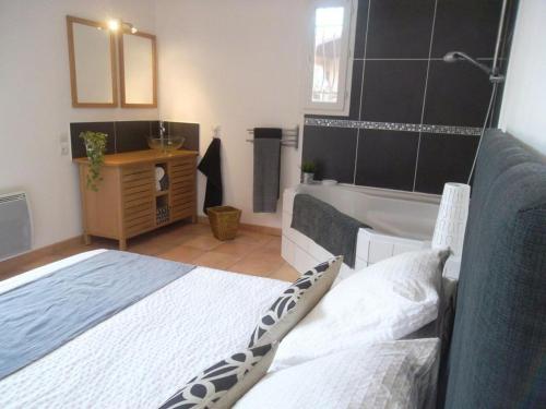 a bedroom with a bed and a bathroom with a tub at Octon, Villa Plain-pied, Piscine in Octon