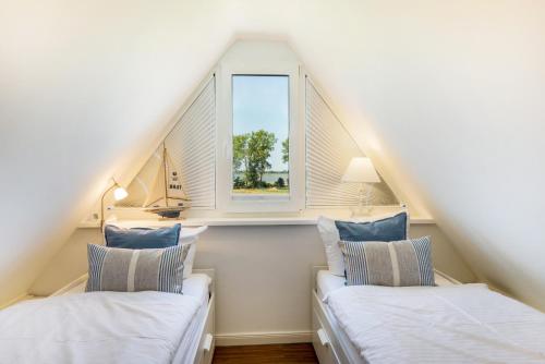 two beds in a attic room with a window at Haus TraumAnker in Bresewitz