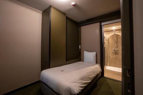 a small room with a bed and a shower at Green Hotel in Genk