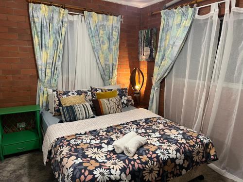 a bedroom with a bed with a comforter and curtains at XYL Pets Friendly Opened Spacious Seaside Boutique Guesthouse in Caloundra