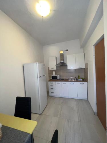 a kitchen with white cabinets and a white refrigerator at Apartments and pansion M&R in Turanj