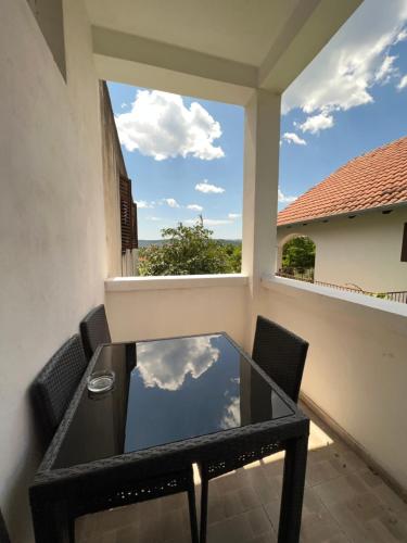 a glass table and chairs on a balcony with a view of the sky at Apartments and pansion M&R in Turanj