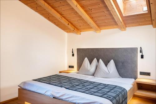 um quarto com uma cama com lençóis brancos e tectos em madeira em Schreiberhof Charme em Laion