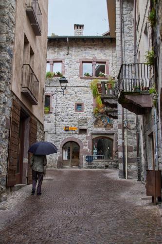 a person walking down a street with an umbrella at Charme nel Borgo di Bienno di Design, Natura & Relax in Bienno