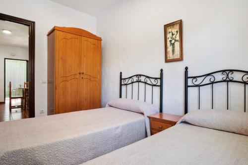 a bedroom with two beds and a wooden cabinet at Casa Paqui 1 in Roche
