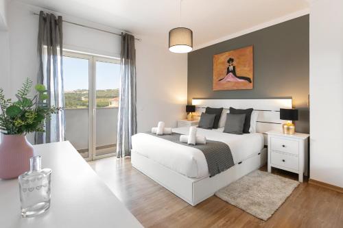 1 dormitorio con cama blanca y ventana grande en Óbidos Pool & Charm, en Óbidos