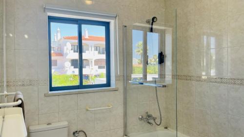 a bathroom with a glass shower with a window at Jardim da Oura by Check-in Portugal in Albufeira