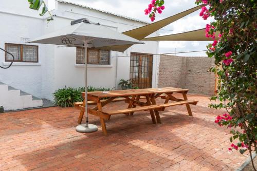 a picnic table with an umbrella on a brick patio at Brinkley's River Village in Klein Brak Rivier