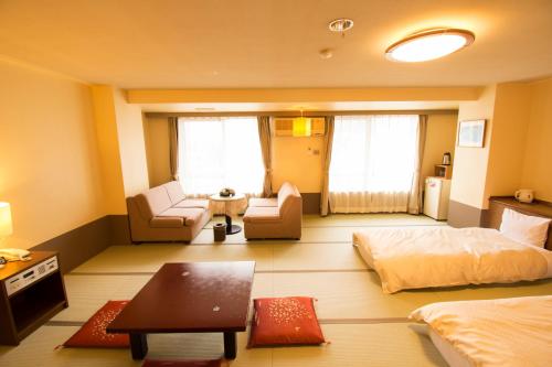 Cette chambre comprend un lit, un canapé et une table. dans l'établissement こんぴら温泉 貸切湯の宿 ことね, à Kotohira