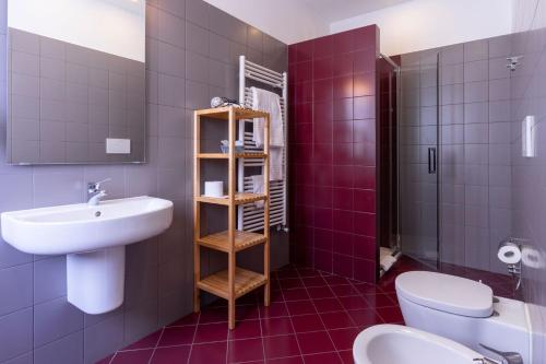 La salle de bains est pourvue d'un lavabo, de toilettes et de carrelage pourpre. dans l'établissement Ventitrémarzo Guest House, à Novara