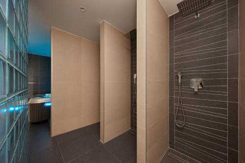 a bathroom with a shower with black tiles at ProFamily Hotel TOP Benecko in Benecko