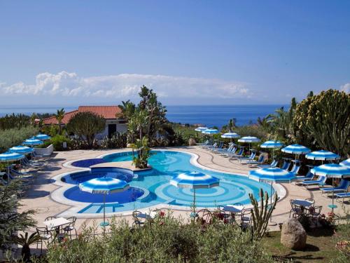- une piscine avec des parasols et des chaises bleus et l'océan dans l'établissement Nice residence in San Nicol di Ricadi with pool, à Ricadi