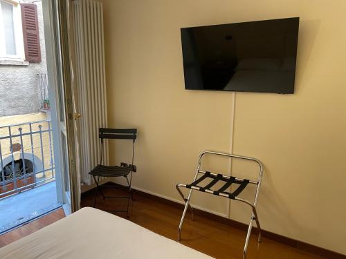 Habitación con silla y TV en la pared. en Casa De Pellegrin Bellagio Lake Como, en Bellagio
