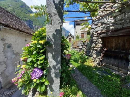 a stone wall with flowers on it next to a building at Casa Coerente Cavergno - Room 1 in Cevio