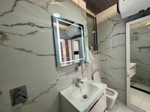 W łazience znajduje się umywalka i lustro. w obiekcie ESTO's Apartament near Tirana Airport 1 - Self CheckIN -Netflix - FREE Parking w mieście Valjiosi