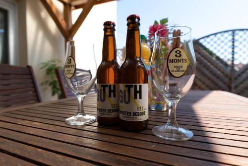 - deux bouteilles de bière assises sur une table en bois avec des verres dans l'établissement Gîte Les Lavandières, à Saasenheim
