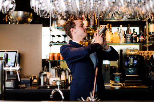 a man in a suit talking on a cell phone in a bar at Dormio Hotel De Prins van Oranje in Maastricht