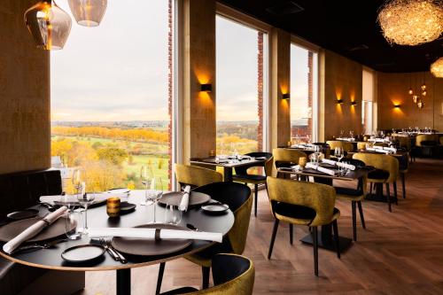 um restaurante com mesas e cadeiras e janelas grandes em Dormio Hotel De Prins van Oranje em Maastricht