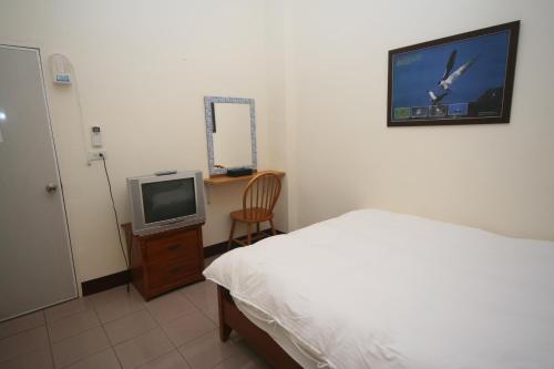 a bedroom with a bed and a tv on the wall at Sunrise B&B in Huxi