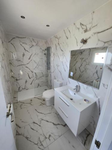 a white bathroom with a sink and a mirror at villa requian in Cacheiras