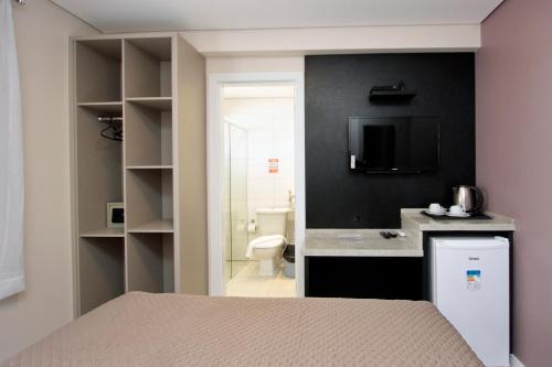 a bedroom with a bed and a bathroom with a toilet at Belluno Apart Hotel in Florianópolis