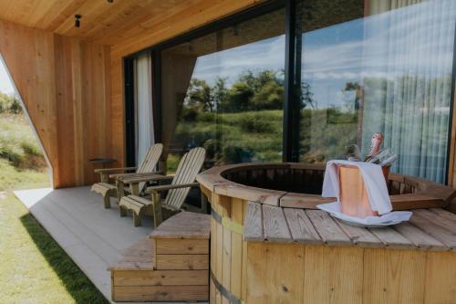 a wooden deck with a hot tub and two chairs at Newton Hall in Chathill