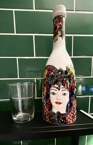 a bottle with a face on it sitting on a shelf with a glass at Casa Siculi in Taormina