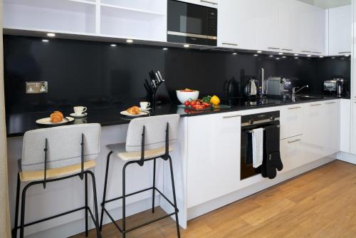 a kitchen with white cabinets and a black counter top at Cheval Harrington Court at South Kensington in London