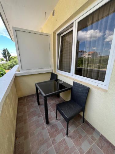 a small balcony with a table and a chair at Apartments and pansion M&R in Turanj