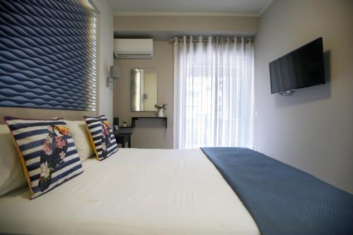 ein Schlafzimmer mit einem großen weißen Bett und einem TV in der Unterkunft Ioanna's Luxury Two Bedroom Apartment in Nafplio