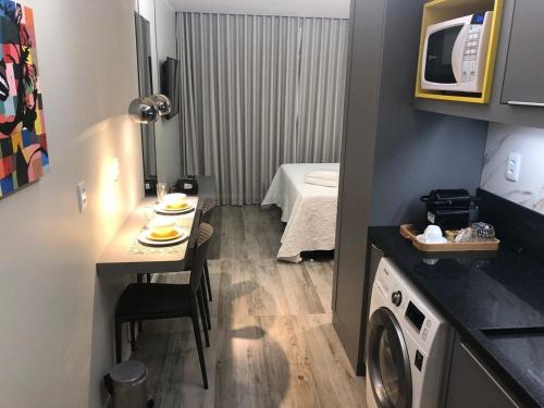 um pequeno quarto com uma mesa e uma máquina de lavar roupa em Flats Asa Norte CLN 110 by CentoEdez em Brasília