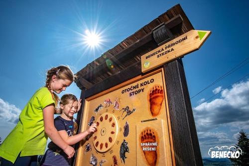 two girls are standing next to a information sign at ProFamily Hotel TOP Benecko in Benecko