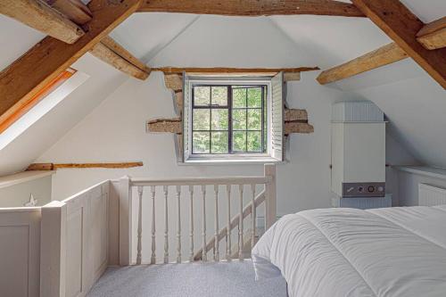 - une chambre mansardée avec un lit et une fenêtre dans l'établissement Mill House Cottage - Star Stay on The Cotswold Way, à Harescombe