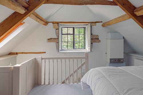 a attic bedroom with a bed and a window at Mill House Cottage - Star Stay on The Cotswold Way in Harescombe