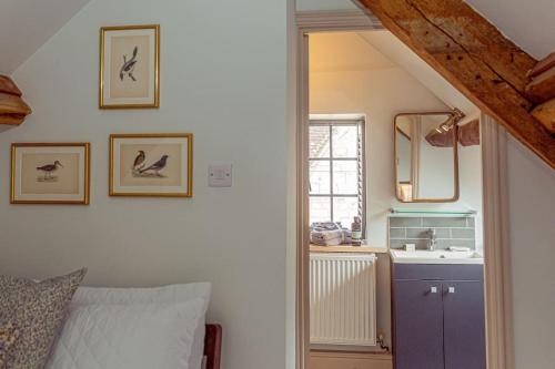 a bedroom with a bed and a sink and a mirror at Mill House Cottage - Star Stay on The Cotswold Way in Harescombe