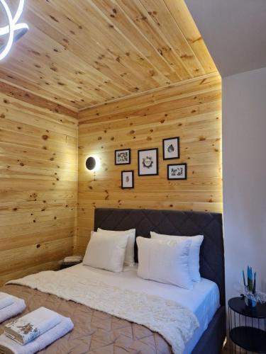 a bed in a room with a wooden wall at OLEA COTTAGE in Ulcinj