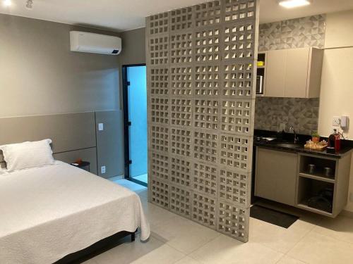 a bedroom with a bed and a wall with a kitchen at Flats Condomínio Park Ville by CentoEdez in Brasília