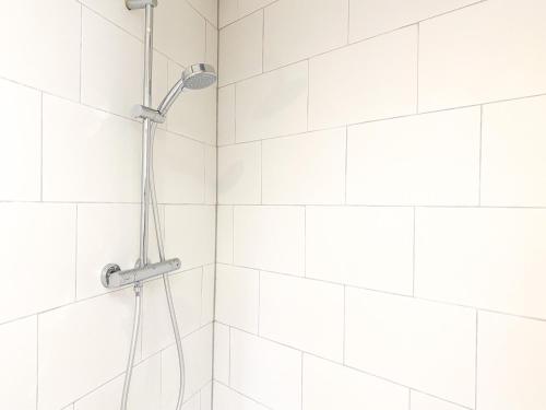 a white tiled shower with a shower head at Vakantiewoning Veere VE01 in Veere