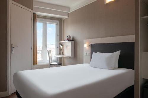 a large white bed in a room with a window at Hôtel Baldi by Magna Arbor in Paris