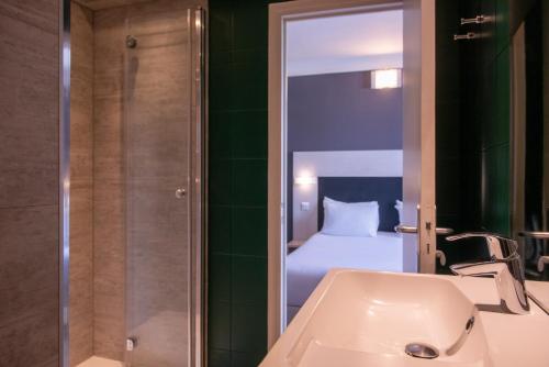 a bathroom with a sink and a bedroom with a bed at Hôtel Baldi by Magna Arbor in Paris
